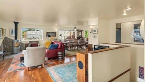 A spacious living area with a fireplace, a red sofa, a dining table, and a kitchen area. - QAnne Hideaway•PrivateDeck•Jacuzzi Tub•CA King•BBQ (Seattle)