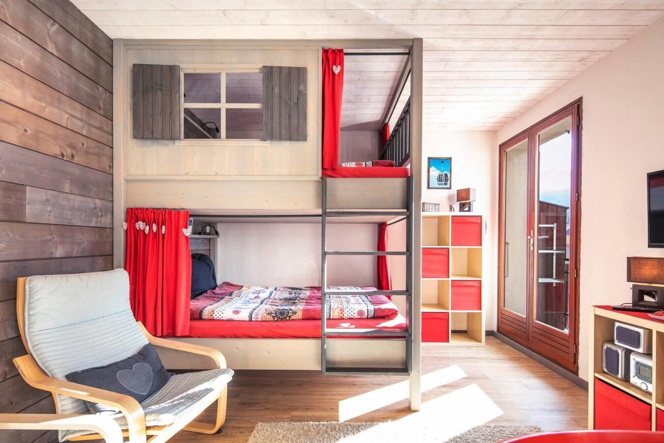 Dormitorio con literas, suelo de madera, un escritorio con computadora y una silla.