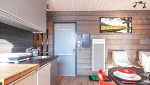 Eine moderne Küche mit Holzwänden, einem eingebauten Ofen und einem Essbereich mit Tisch für zwei Personen.