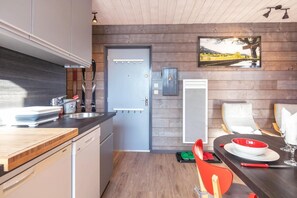 A modern kitchen with wooden walls, a built-in oven, and a dining area with a table set for two. - Ground floor, balcony, tv, 24m², Villard de Lans (Villard-de-Lans)