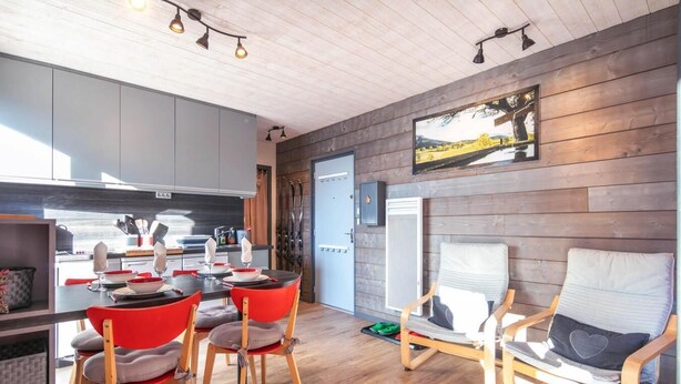 Eine moderne Küche mit Essbereich, Holzwänden und einem großen Fenster.