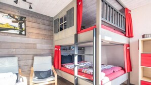 Ein Schlafraum mit Etagenbetten, einer Holzwand, einem Schreibtisch und einem Stuhl.