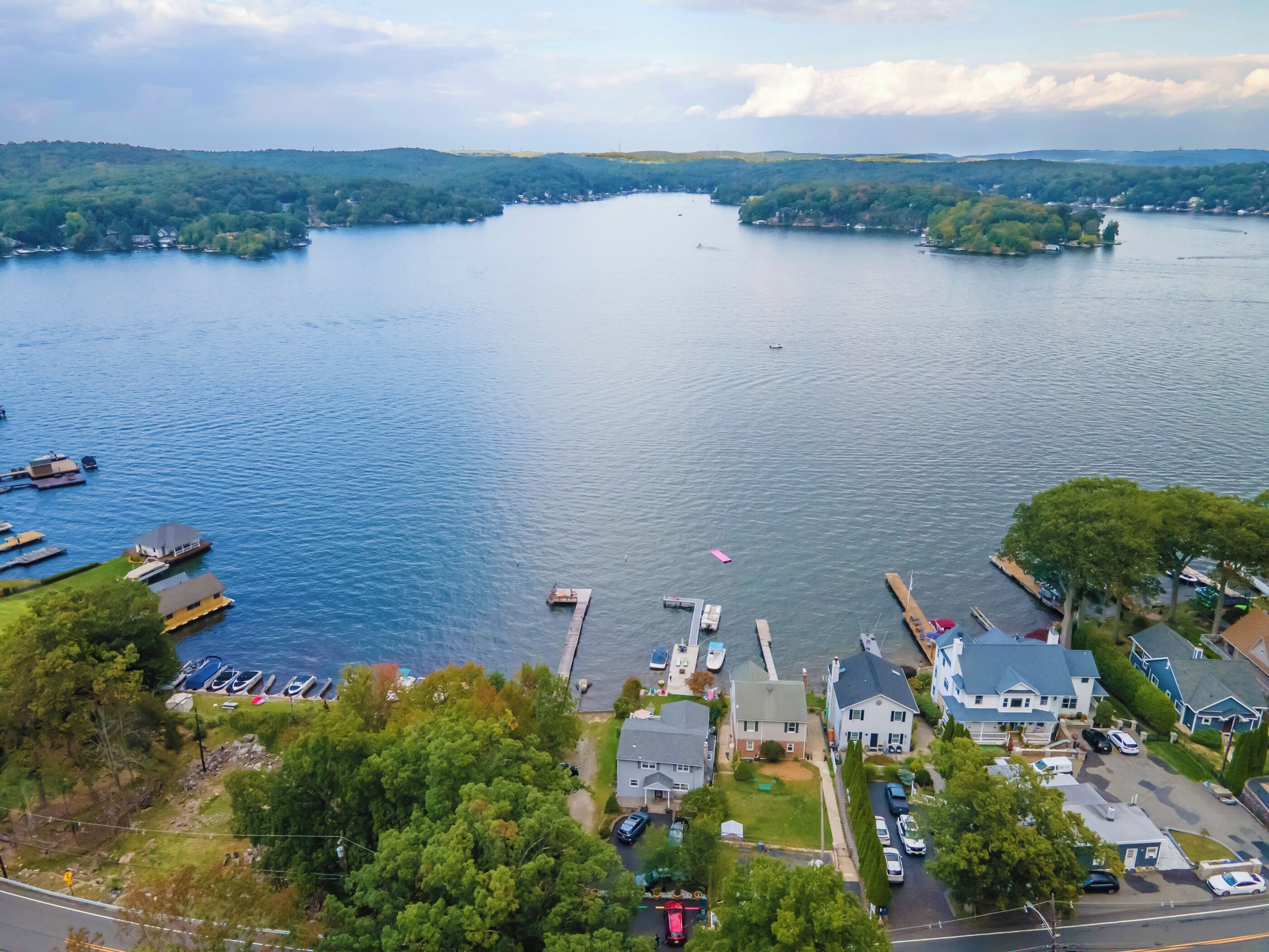 Vista aérea de una comunidad junto al lago, con barcos amarrados, casas y una carretera que conduce al agua.