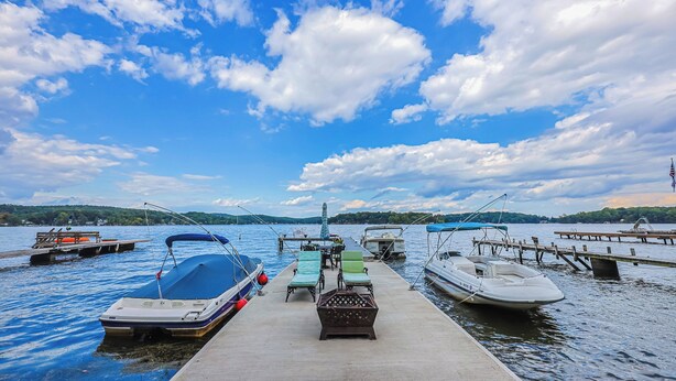 Un quai avec des bateaux, une jetée en bois et un lac paisible sous un ciel partiellement nuageux.