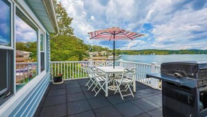 Un balcon avec une table et des chaises, un barbecue et une vue sur un lac.