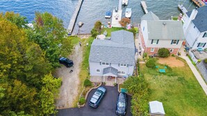 Un quartier résidentiel comprenant une maison, deux voitures, un quai et un bateau.