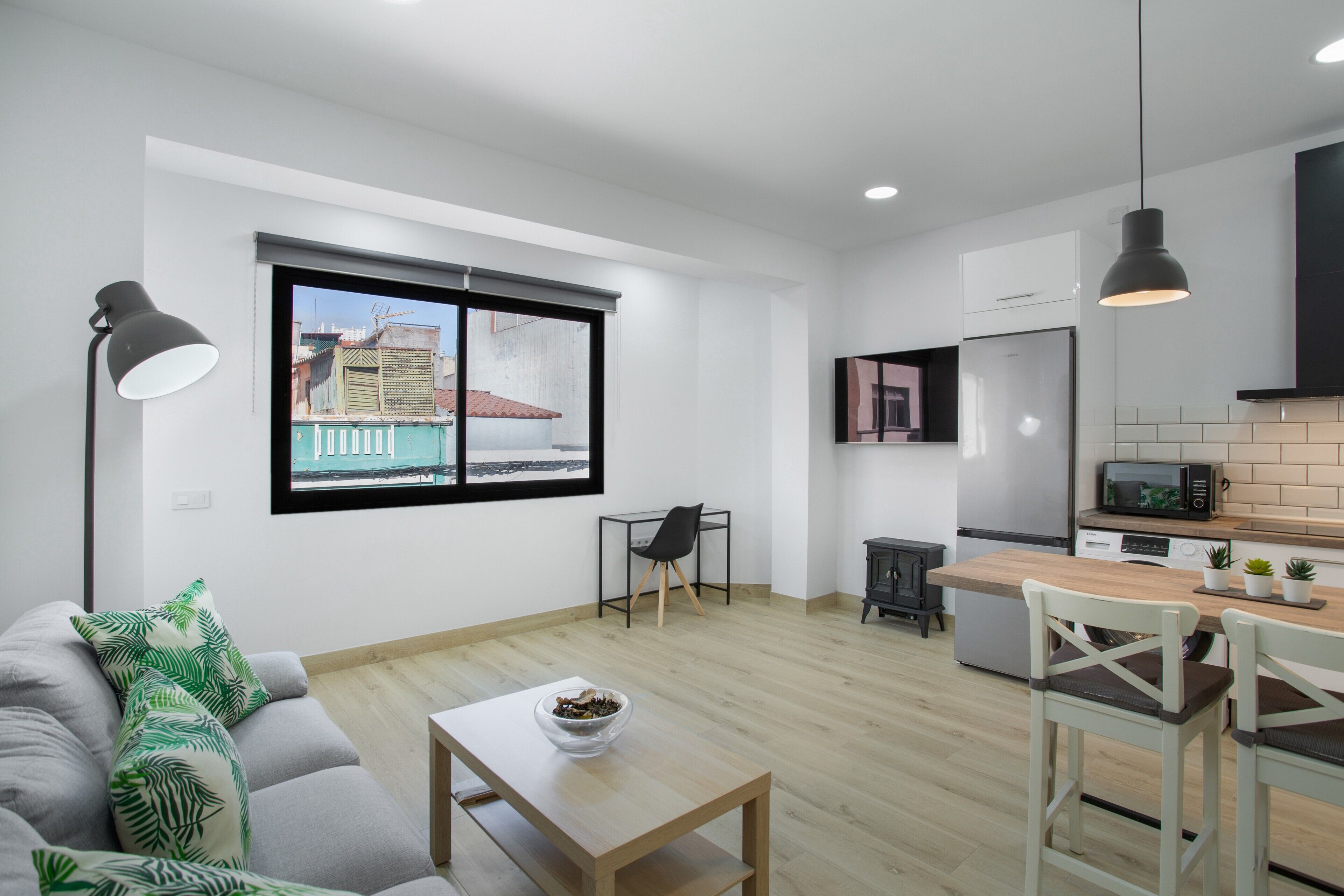 Een modern appartement met een eethoek, keuken en een groot raam met uitzicht op de stad.