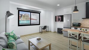 Een modern appartement met een eethoek, keuken en een groot raam met uitzicht op de stad.