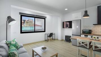 Een modern appartement met een eethoek, keuken en een groot raam met uitzicht op de stad.