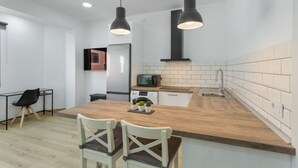 Een moderne keuken met een houten kookeiland, twee hanglampen, een magnetron en een spoelbak.