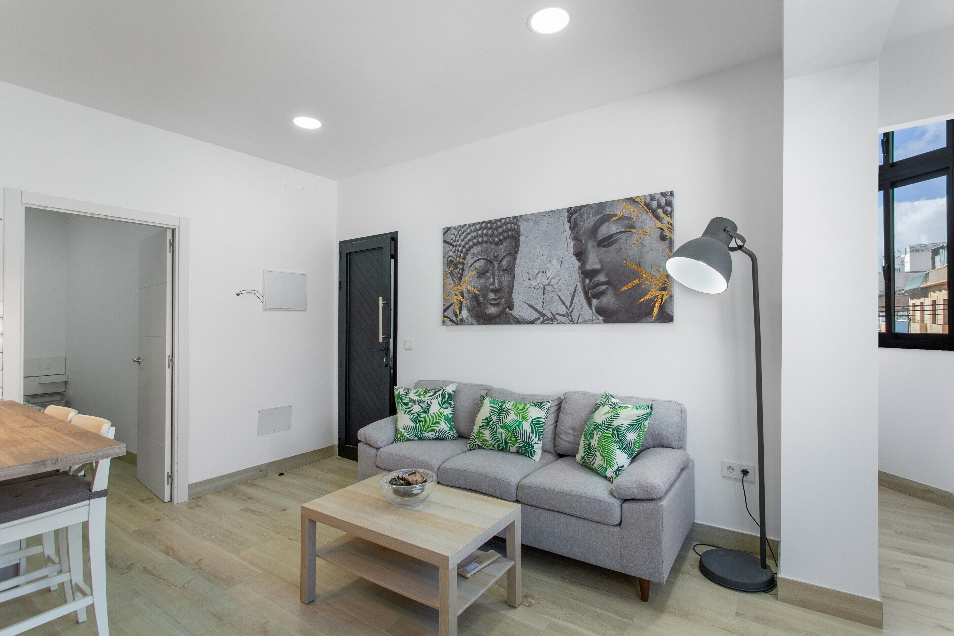 Ein modernes Wohnzimmer mit einem grauen Sofa, einem Holztisch, einer Stehlampe und einem Wandbild.