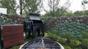 A barbecue grill and a wooden cabinet in a garden setting.