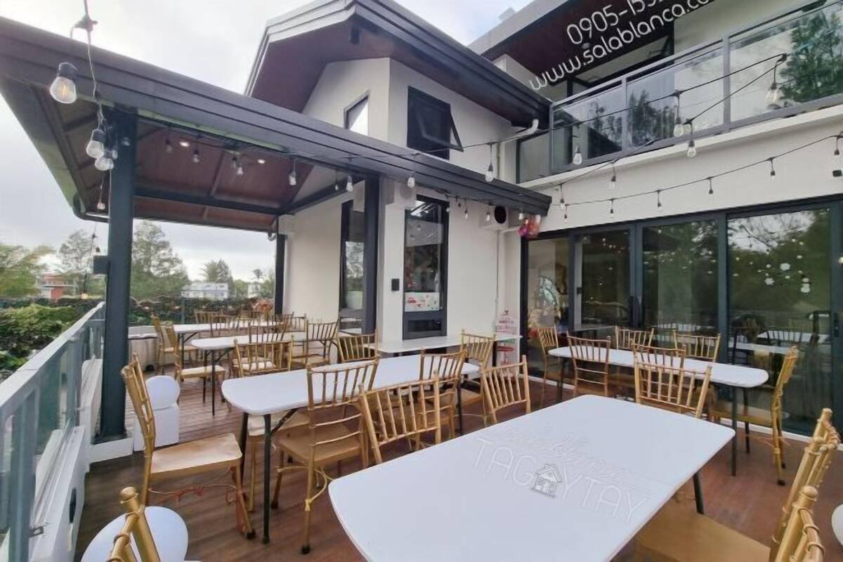 An outdoor dining area with tables and chairs, a covered section, and a building with a website address.