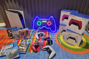 Peliasennus, johon kuuluu PlayStation 5 -konsoli, kaksi PlayStation-ohjainta ja useita pelien koteloita.