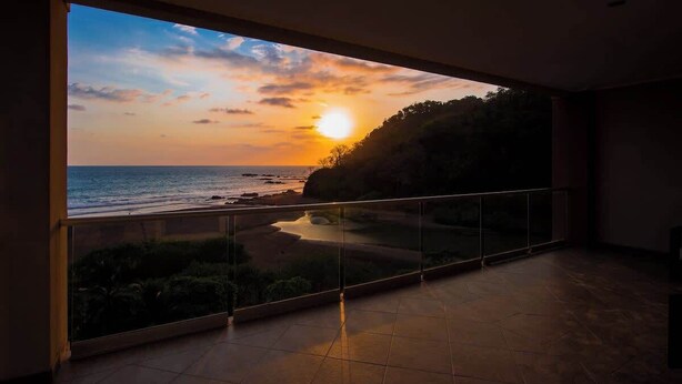 A balcony with a view of the sunset over the sea. - Direct Beach Front Ocean View on 7th Floor (Jacó)