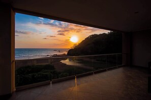 Un balcon avec vue sur le coucher de soleil sur la mer.