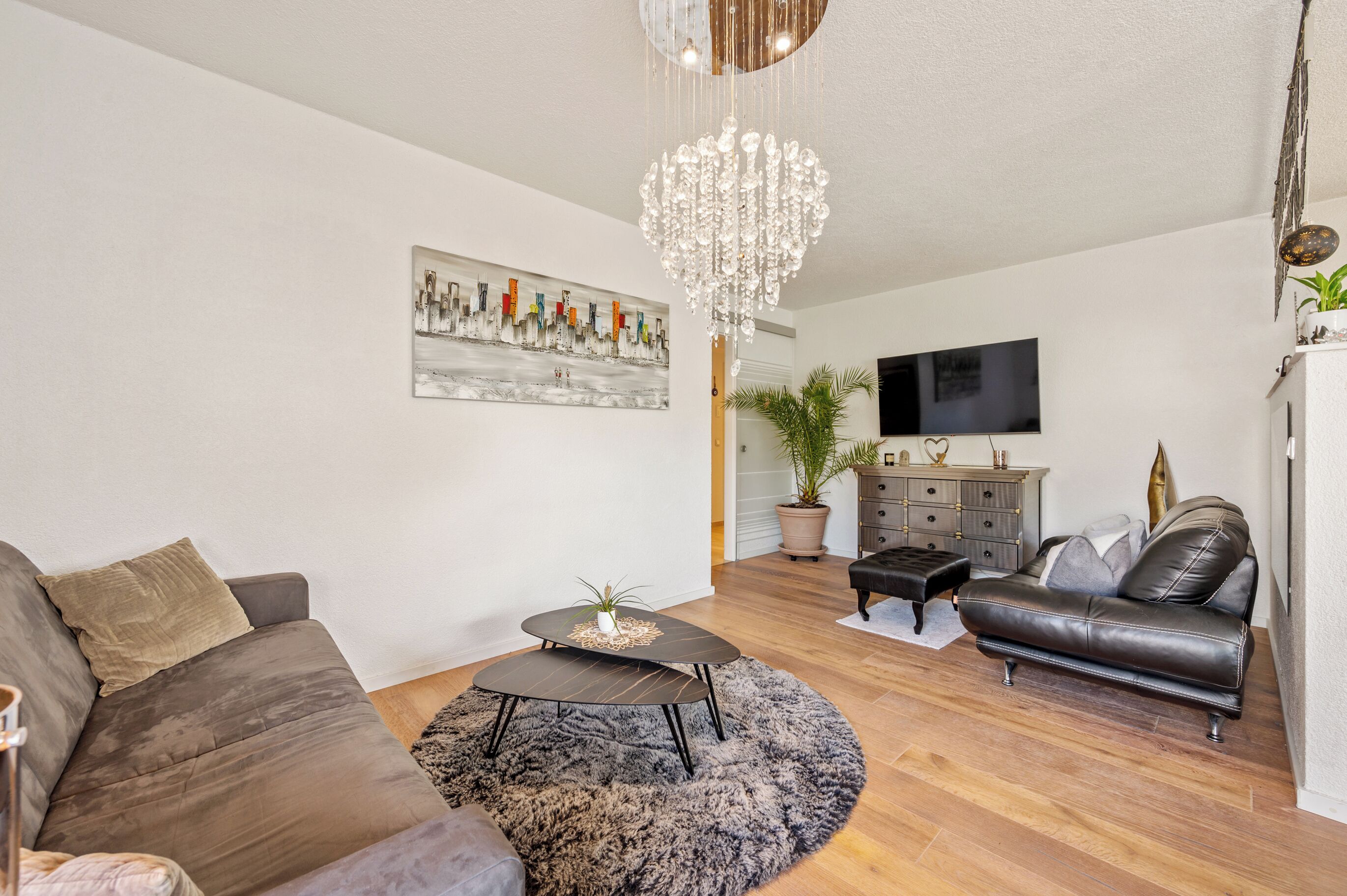 Ein modernes Wohnzimmer mit einer Couch, einem Couchtisch und einer Deckenleuchte.