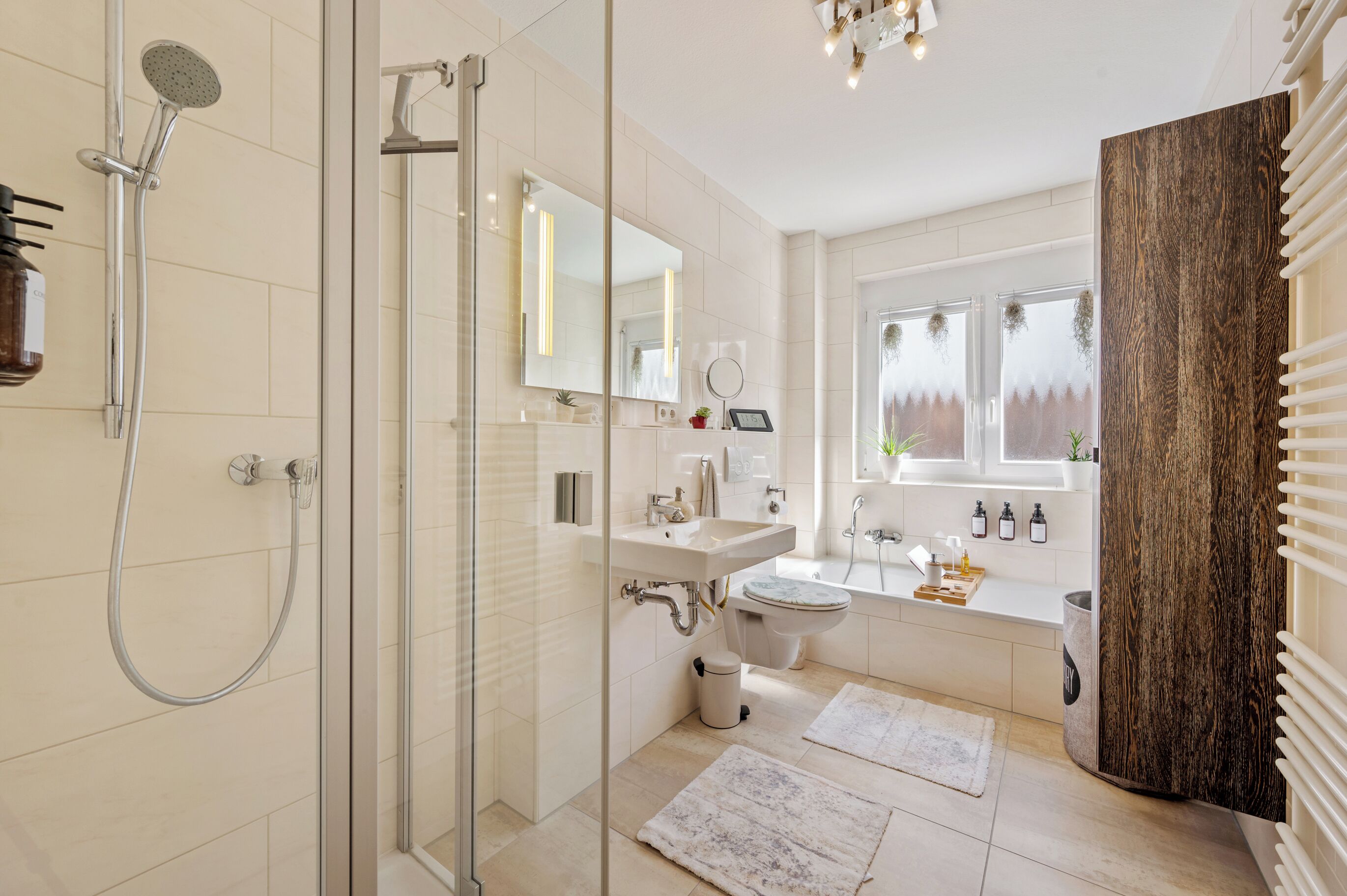 A modern bathroom with a glass shower enclosure, a white sink, a toilet, and a large mirror.