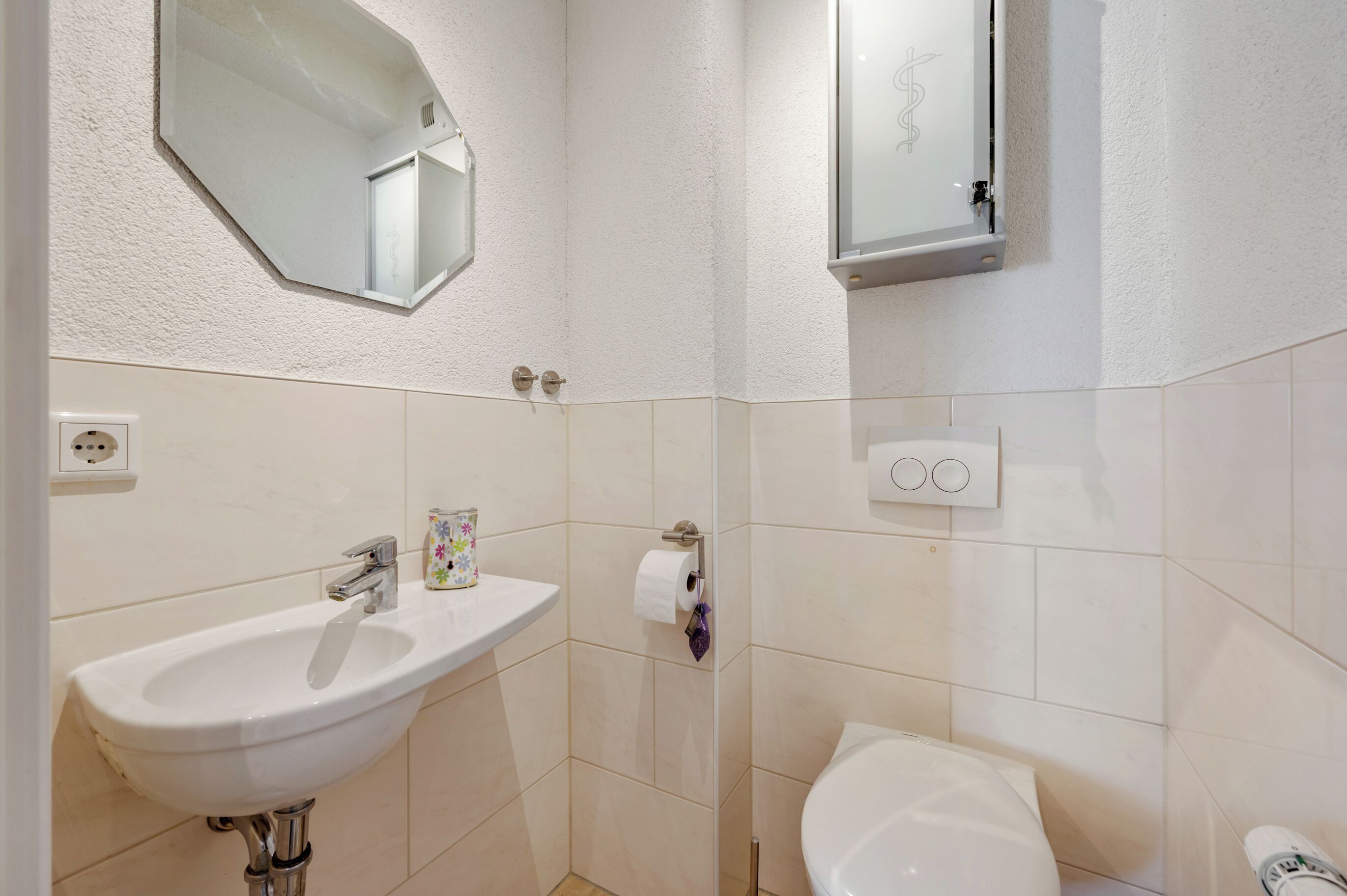 Une salle de bain avec un lavabo blanc, un miroir et des toilettes.
