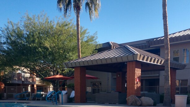 A pool area with a covered seating area, lounge chairs, and a 'No Diving' sign.
