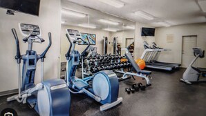 A gym with exercise equipment including a treadmill, elliptical, and weight machines.