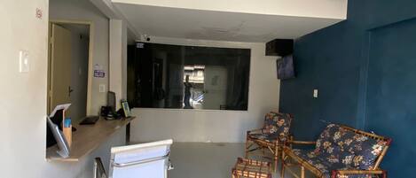 A reception area with a reception desk, a waiting area with wicker chairs, and a large mirror on the wall.