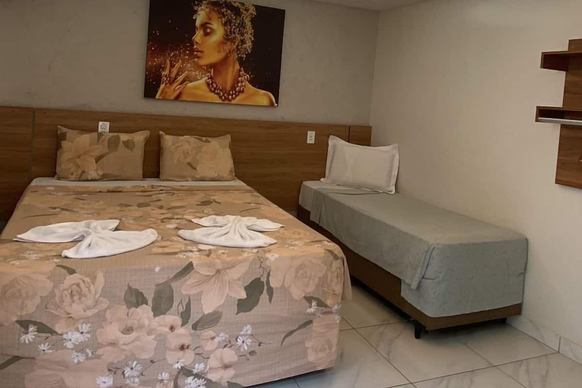 A bedroom with a bed, a bench, a painting, and a ceiling light fixture.