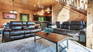 A cozy living room with leather sofas, a wooden coffee table, and a staircase.