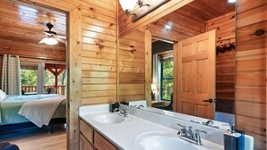 A wooden cabin-style bathroom with two sinks, a large mirror, and a ceiling fan.