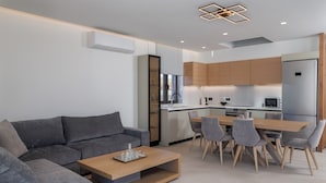 Una sala moderna con un sofá gris, una mesa de centro de madera y un comedor con sillas grises.