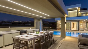 Un espacio para comer al aire libre con piscina y pared de piedra.