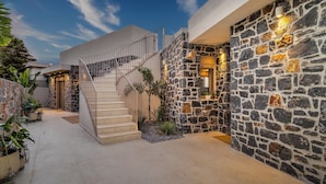 A modern building with a stone facade, a staircase, and potted plants.
