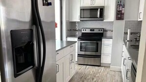 Une cuisine moderne dotée d’appareils électroménagers en acier inoxydable, de meubles blancs et d’un dosseret carrelé.