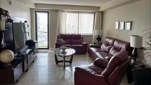Un salon avec un canapé, une table basse, un téléviseur et une lampe.