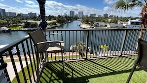 Un balcon avec vue sur une rivière, des palmiers et le panorama de la ville.