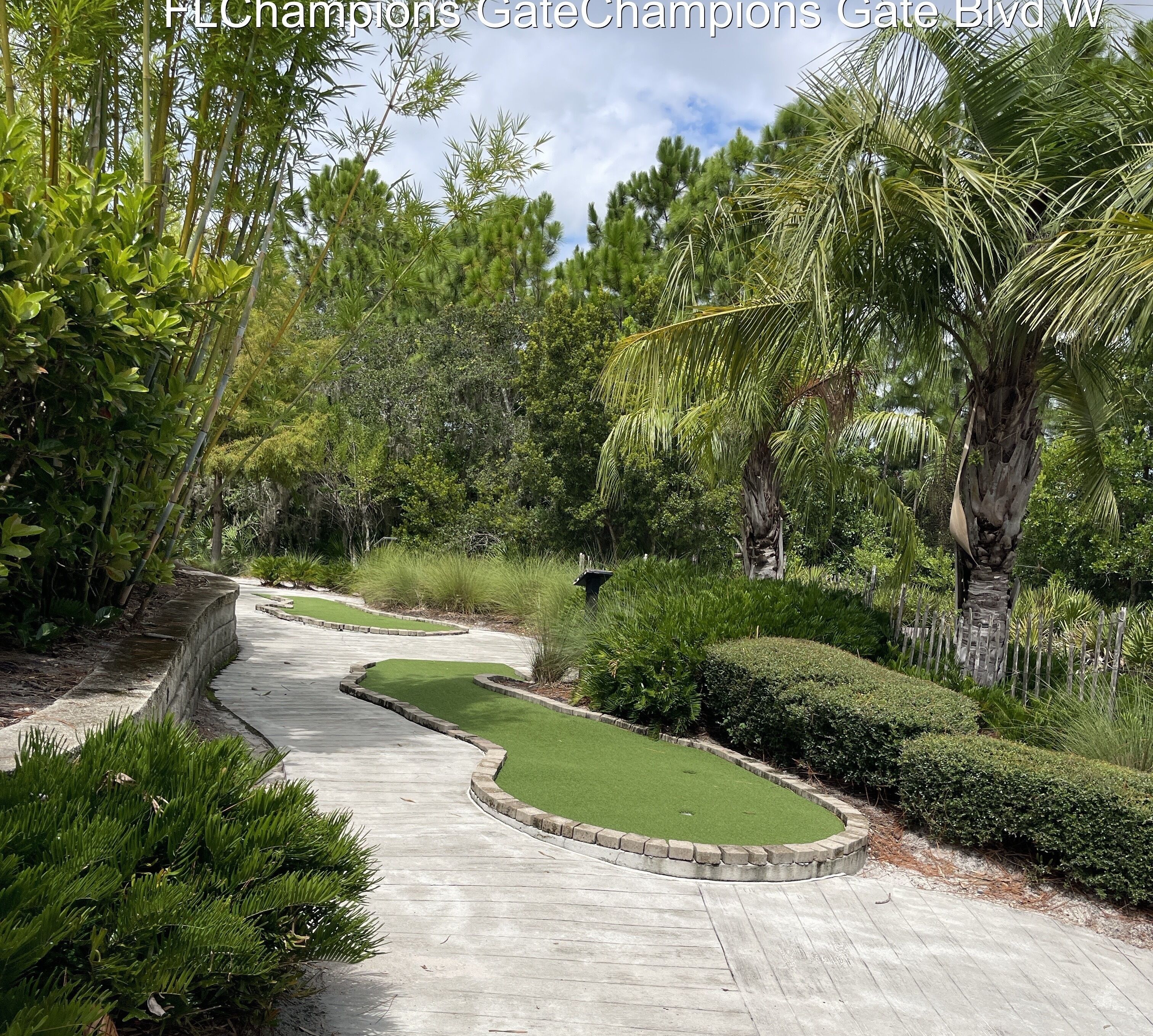 Un campo de golf con un sendero serpenteante, césped cuidado y diversas plantas tropicales.