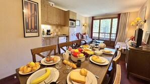 A dining area with a wooden table set for a meal, a kitchen in the background, and a ski club sign on the wall. - 3rd floor, swimming pool, terrace, parking, tv, ski locker, 58m², Vars (Vars)