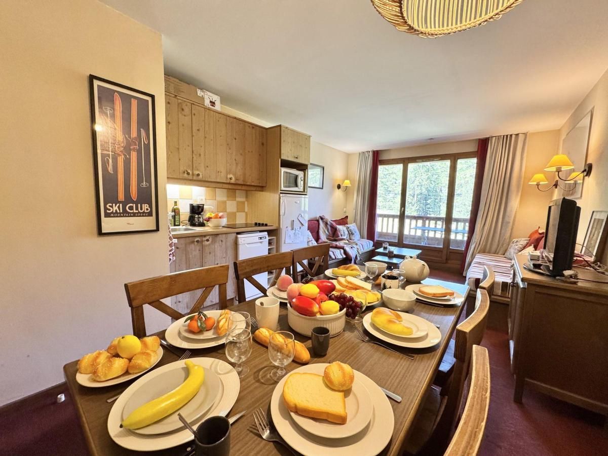 A dining area with a wooden table set for a meal, a kitchen in the background, and a ski club sign on the wall.