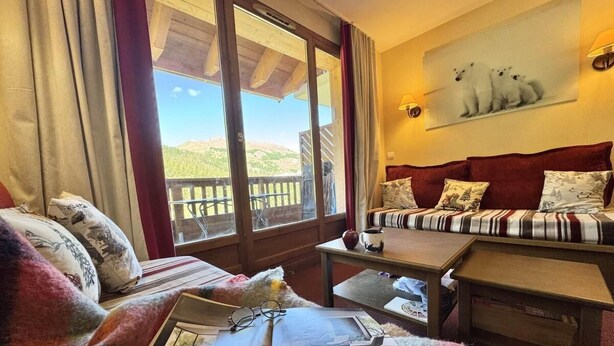 A cozy room with a sofa, a small table, and a window with a view of hills. - 3rd floor, swimming pool, terrace, parking, tv, ski locker, 58m², Vars (Vars)