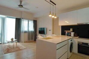 A modern kitchen with a central island, a built-in oven, and a washing machine.