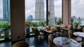 Un restaurante moderno con amplios ventanales que ofrecen vistas de dos edificios altos.