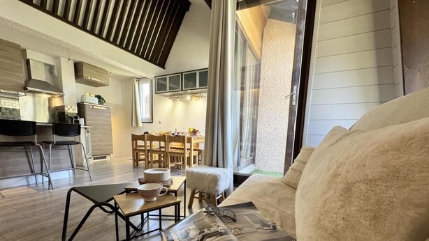 A cozy living room with a sofa, a coffee table, and a dining area with chairs.