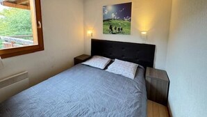 A bedroom with a bed, two bedside tables, a window, and a painting on the wall. - 350m from ski slopes, 3rd floor, view ski slopes, balcony, 33m², Serre Chevalier (Saint-Chaffrey)