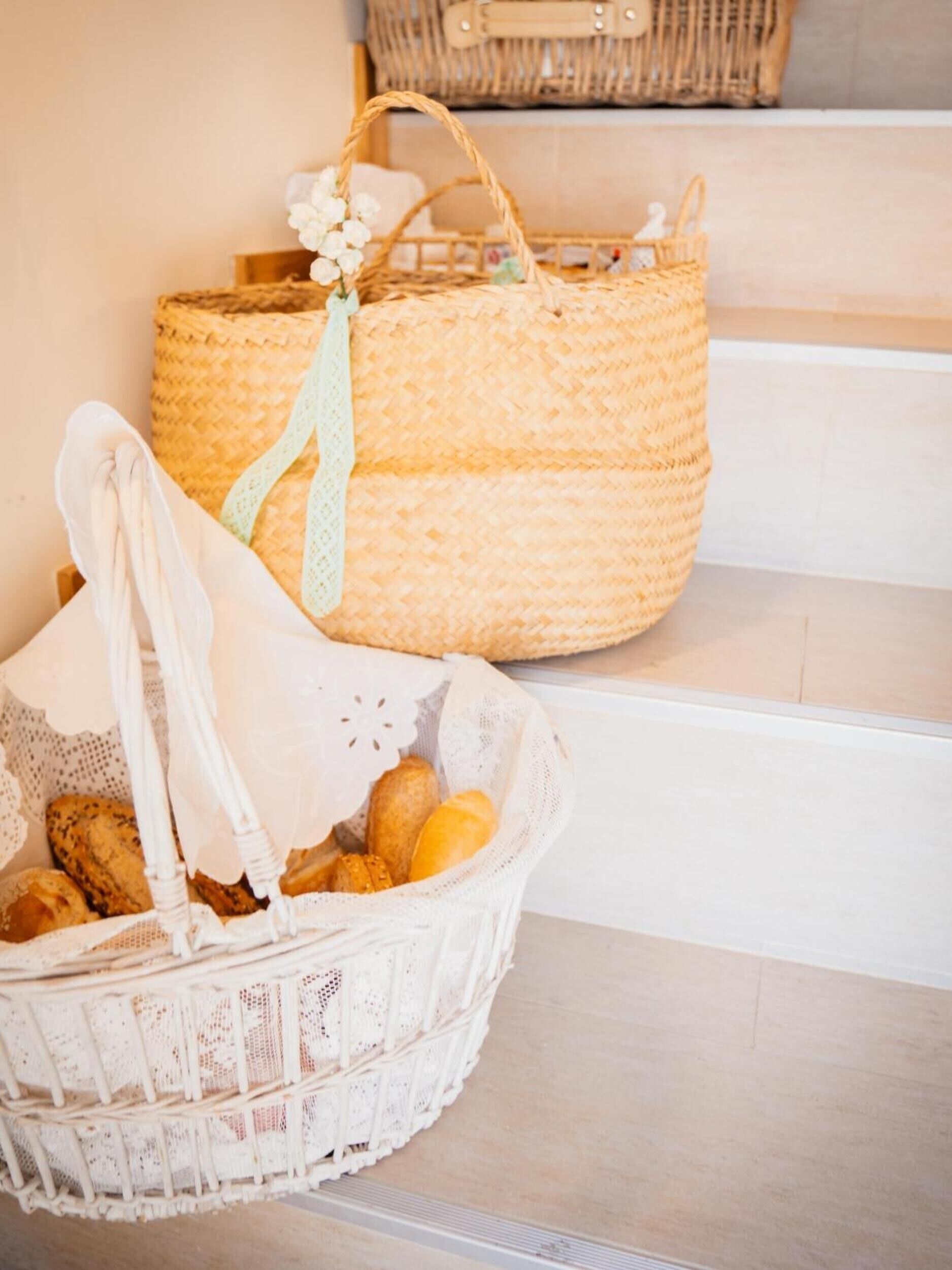 A wicker basket with bread and a white cloth bag on a staircase.