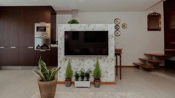 Un salon moderne doté d’un téléviseur à écran plat fixé au mur, d’un four encastré et d’un escalier menant à un niveau supérieur.