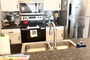 A modern kitchen with a microwave, stove, and stainless steel refrigerator. - Lakefront Condo/Strip/2nd Week August Deal + Pool (Osage Beach)