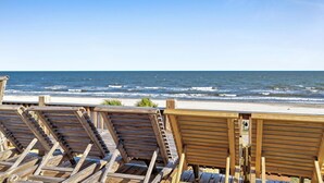 Houten strandstoelen gericht op de oceaan.