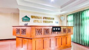 Una reception con una targa che riporta 'Wisma Syariah Atma Bhakti' e il logo 'OYO'.