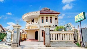 Un edificio con un cartello che riporta la scritta "WISMA SYARJAH ATMA BHAKTI" e un ingresso chiuso da un cancello.