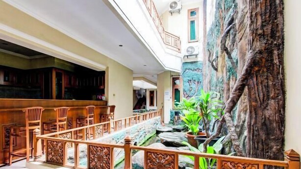Un'hall d'albergo con una scala in legno, un'area salotto e un grande murale raffigurante un albero.